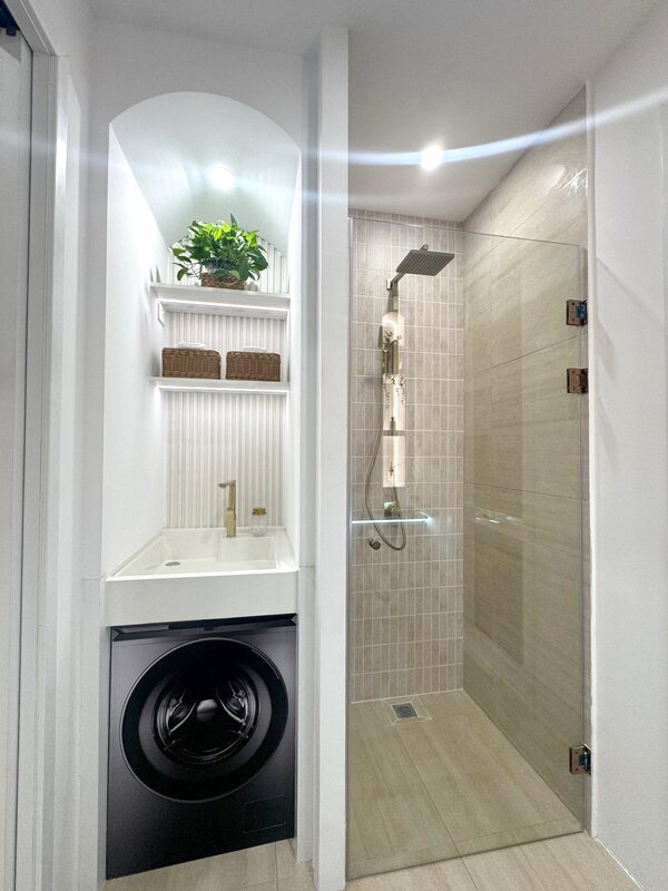 Glass shower beside a laundry nook with washing machine